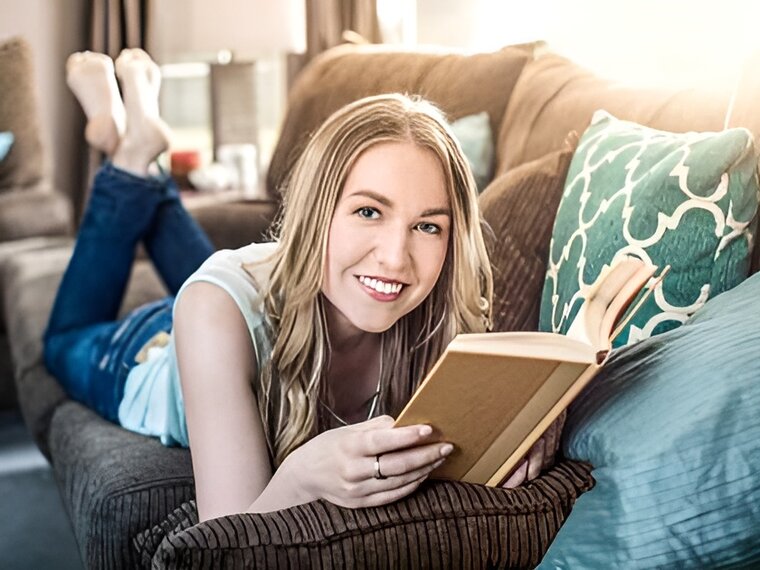 Eine Frau liest auf dem Sofa ein Buch